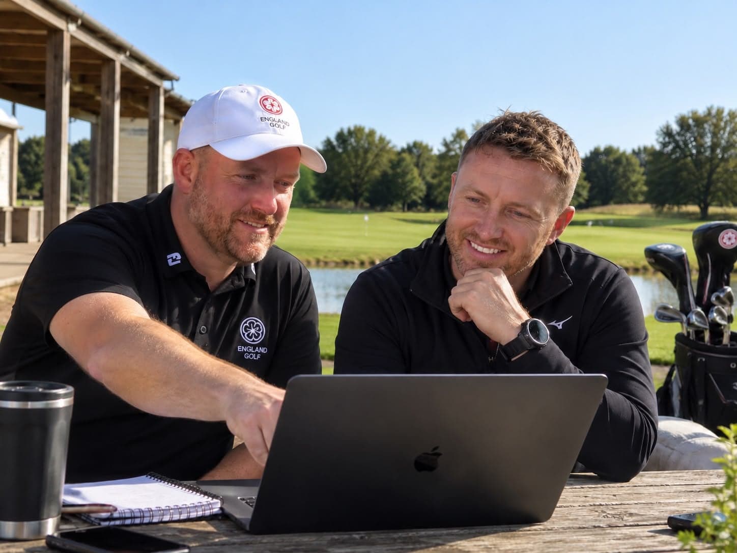 Ollie Greenham and Alex MacDougall looking at a laptop together at a golf club
